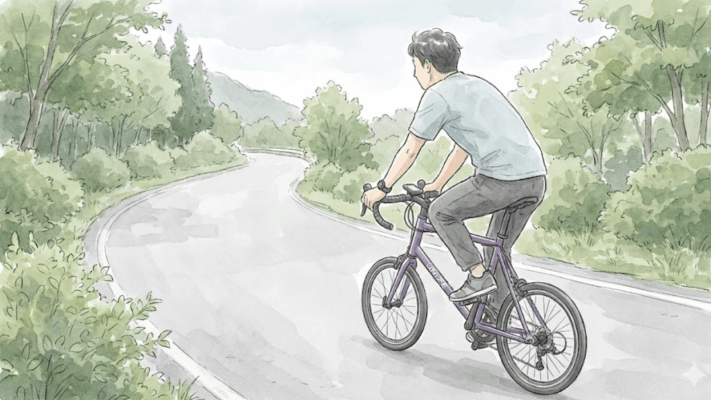 緑に囲まれたカーブの道をミニベロで走る人物の後ろ姿